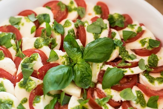 Caprese mit Tomaten, Mozzarella und frischem Basilikum auf einem Teller angerichtet