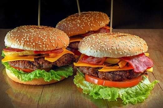 Verschiedene Burger mit Salat, Käse, Tomaten und Sesambrötchen auf einem Tisch angerichtet