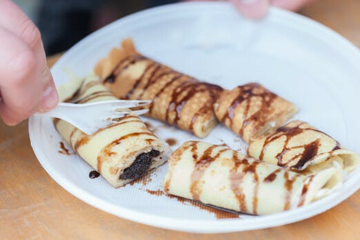 Süße Vorspeise mit gefüllten Teigrollen und Schokoladensauce auf einem Teller serviert.